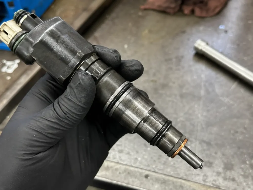 Ford 7.3 Powerstroke Injector Size Chart: Stock Codes and Upgrade Stages by Year 2026 3 7.3 Powerstroke HEUI fuel injector held by mechanic showing copper crush washer
