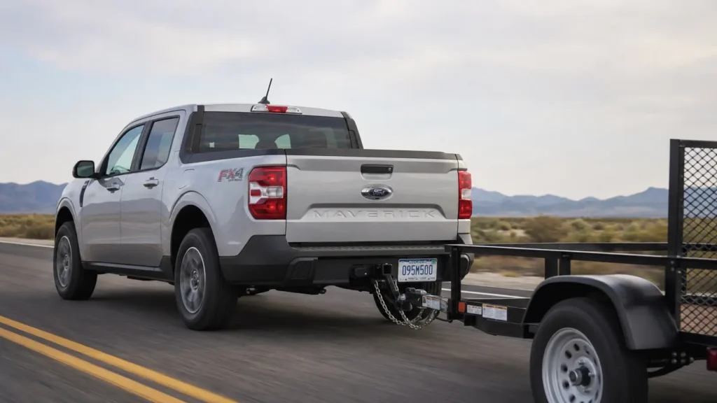 Ford Maverick Towing Capacity by Year: 2022–2026 Complete Chart 2 2022–2025 Ford Maverick compact pickup in silver towing a small utility trailer on a highway, rear three-quarter view showing the hitch receiver and trailer tongue connection.