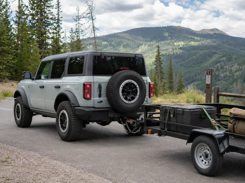 Ford Bronco towing a utility trailer showing factory hitch receiver and tow setup