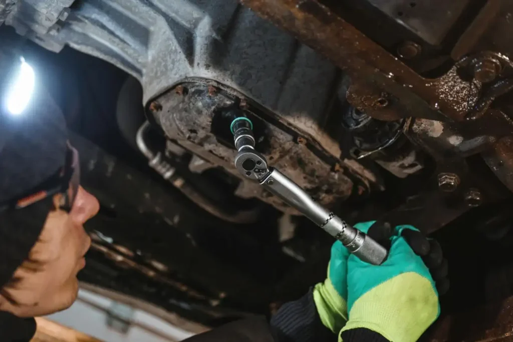 Technician using a torque wrench on Ford 2.7 EcoBoost oil-pan bolts.
